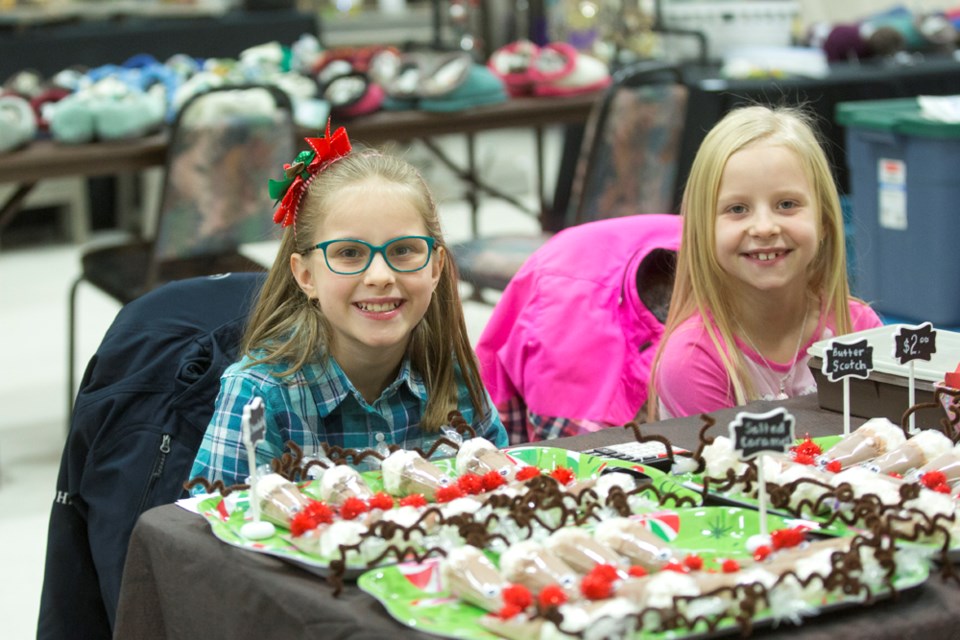 Sisters Caydence and Paige Bohn sit at their table, filled with fun little treats at the Visual Arts Centre&#8217;s annual Christmas craft sale on Dec. 2, at the Rec. Centre. 