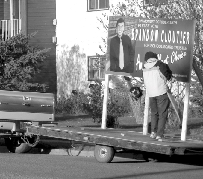 Trustee candidate Brandon Cloutier takes down his sign the day after losing his NLSD campaign to incumbent Danny Smaiel in a close race.