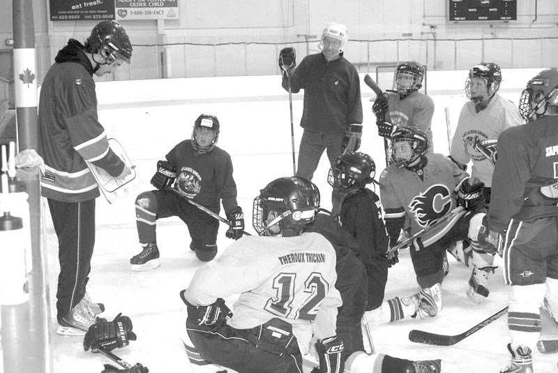 Voyageurs player Blair Hawes teaches kids on the Atom &#8220;C&#8221; team a few hockey tips.