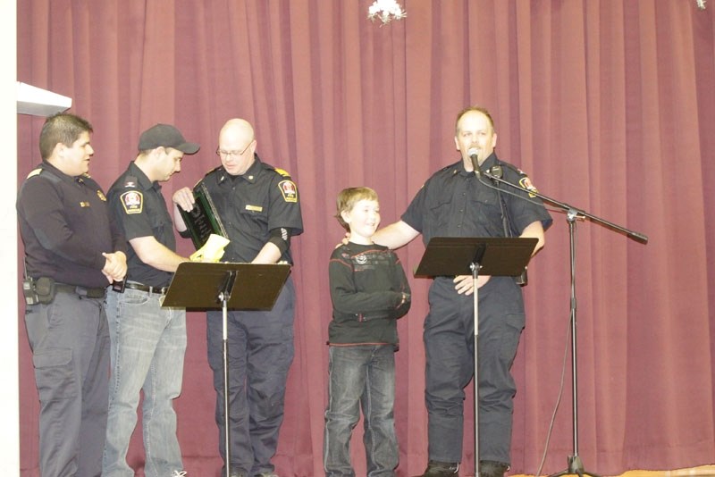 Elijah Skoglund, 8, receives a hero award from members of the area&#8217;s fire departments for rescuing his brother from a rain barrel last summer