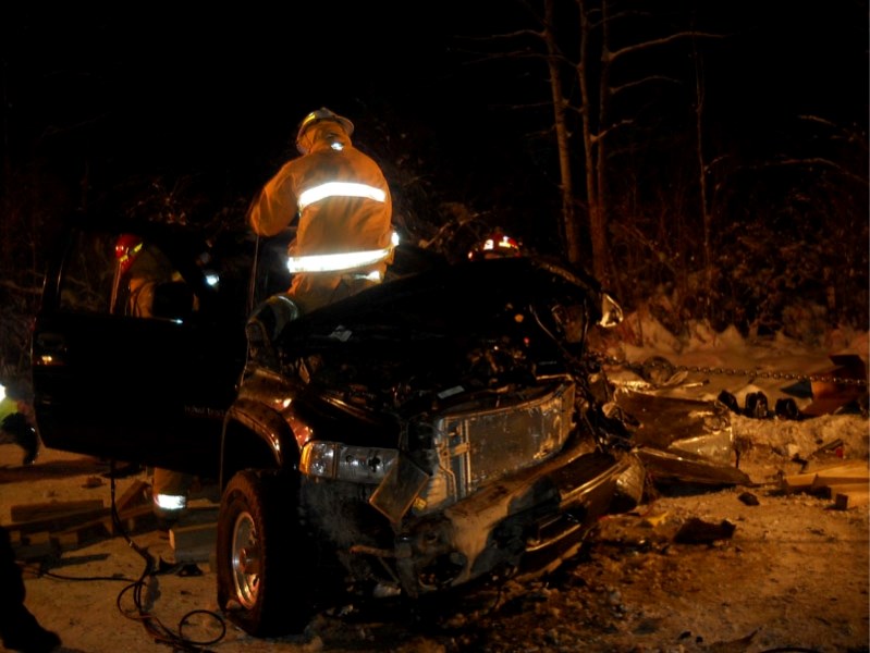 Firefighters attempt to get the 40-year old driver out of his pick-up truck after he crashed into a empty logging truck on the old Conklin road.