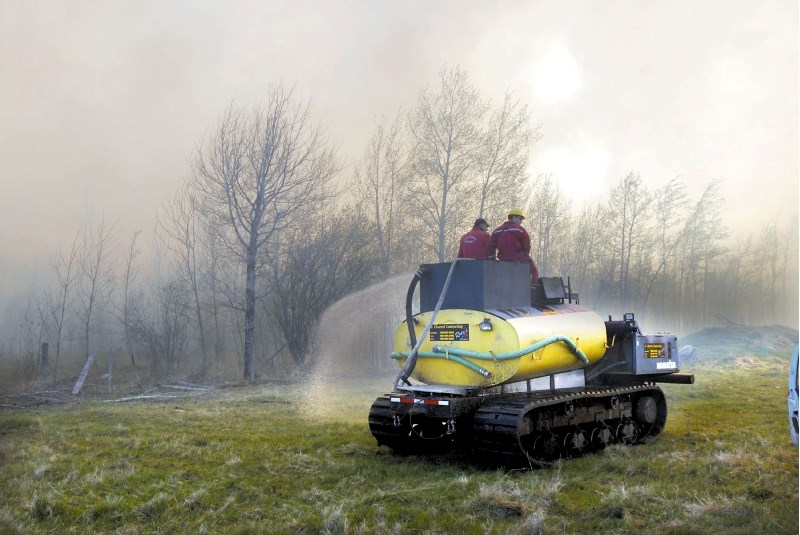 Lac La Biche County firefighters attempt to control the spread of a wildfire near Venice by soaking the perimeter. County fire crews were also battling blazes near the Fork