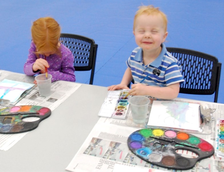 Big sister Kaylin Weening, 4, focuses on her water colour masterpiece as her brother Silas, 2, takes a moment out from his butterflies and trees to smile happily for the