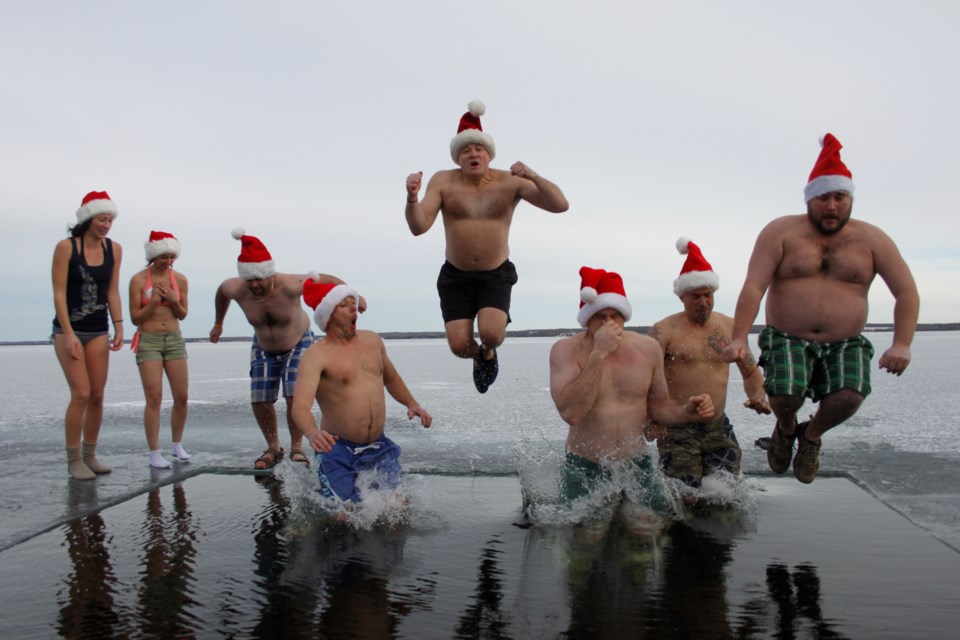 Mike Dempsey (centre) catches some air for one of his patented cannonballs as the other Polar Bear Dippers make their annual leap into the frigid waters of Lac La Biche Lake