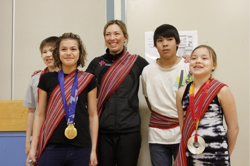 Beckie Scott shares some of her Olympic medals with Kikino School students Feb. 29, (from left) Ross Laviolette, Brenna Cey, Scott, Spencer Blyan, and Carson Macnamara.