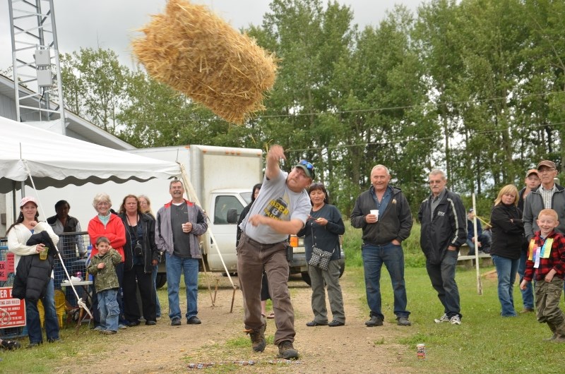 Former Hylo Harvest Festival King Trevor Rolph mightily tosses a hay bale during the King and Queen competitions at the Hylo-Venice Agriplex on Saturday, August 25. Trevor