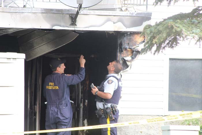 A Lac La Biche RCMP constable talks with a fire investigator on Wednesday afternoon outside the burned apartment.