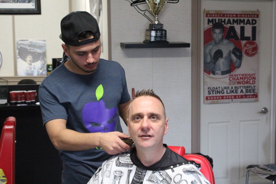 Omar Saleh of Omar&#8217;s Barber Shop cuts Dave Brewster&#8217;s hair last Friday as part of his monthly fundraising effort. This month, it was about a six-year-old girl
