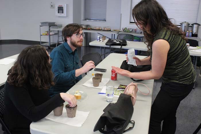  Lindsay Kozakevich provided attendees with seeds and pots of soil. She hands out some seeds to Luke Muise as she demonstrates how to place them in the pot.