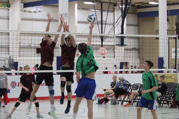  Zone 7 player smashes the ball while Zone 9 players (who placed 1st place) leap up to block during Men's Volleyball qualifier round on Saturday