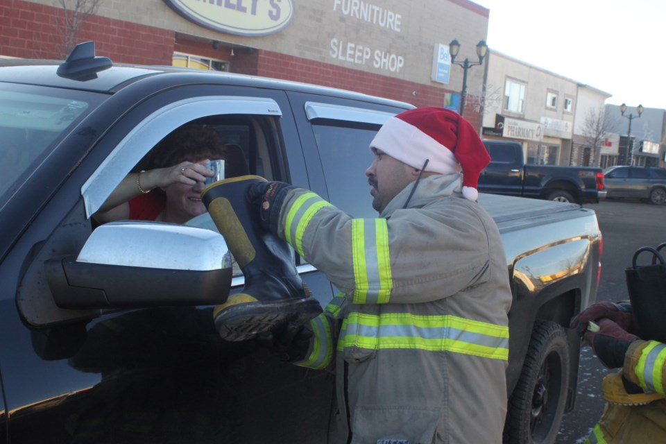 Ivan Alvarado, a firefighter with Lac La Biche County Fire Rescue, receives a donation from a passerby during the boot drive held Saturday to raise money for toys and food hampers for local families in need. Chris McGarry photo. 