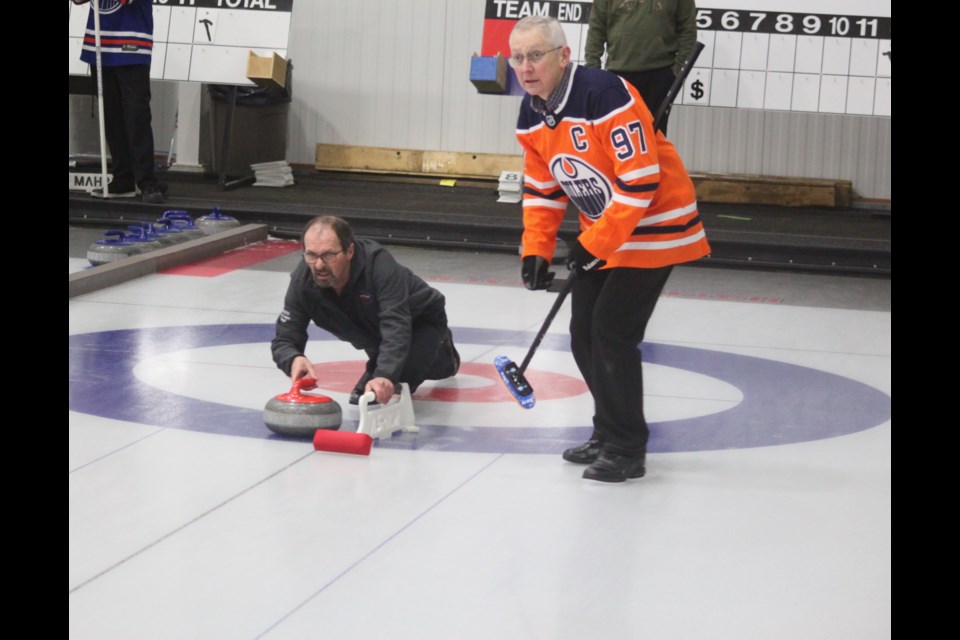Rosaire Tardif (standing, wearing Edmonton Oilers jersey), looks down the ice as teammate Ken Beniuk prepares to slide the rock. The team led by Beniuk came in as the third-place winners in the Lac La Biche and District Curling Club’s annual Men’s Curling Spiel, which took place on Saturday, Jan. 18. Chris McGarry photo.