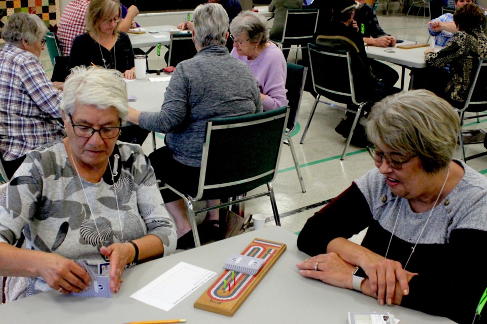 Lucille Burdek gets ready to deal out some cards while Marie Warawa looks on. 