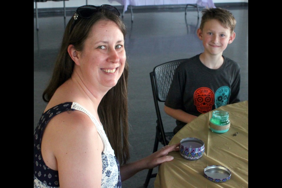 Katrina Mamela and her son, Kagen, hold up the colourful candles which they had made during The Art of Conversation event and had just finished decorating. The theme of the July 10 workshop-which was held at McArthur Place from 7-8:30 p.m.- was candle making. There will be a watercolour workshop on July 17 and one focusing on Indigenous artwork on July 24. Chris McGarry photo. 