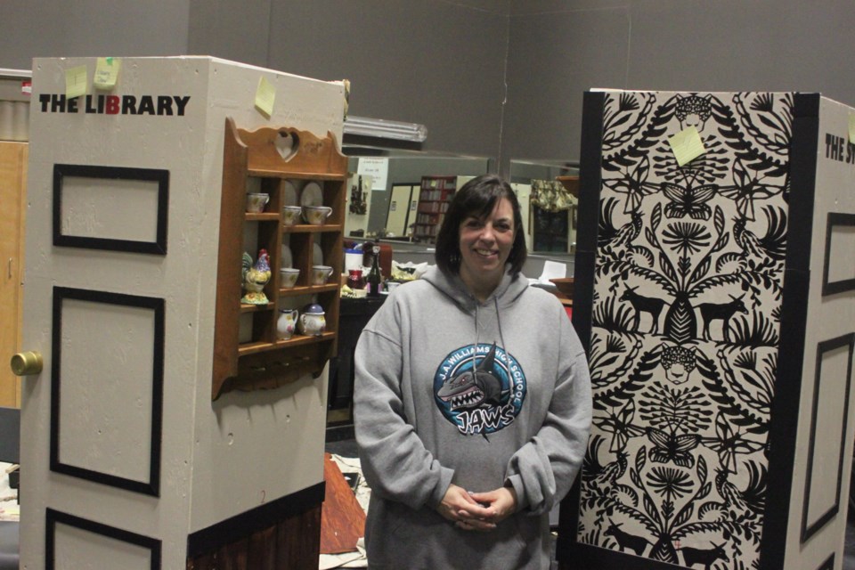 Marlo Hanson, a drama teacher at JA Williams High School, stands between two of the sets which will be used for the school's production of Clue, which takes place from Dec. 13-15. 