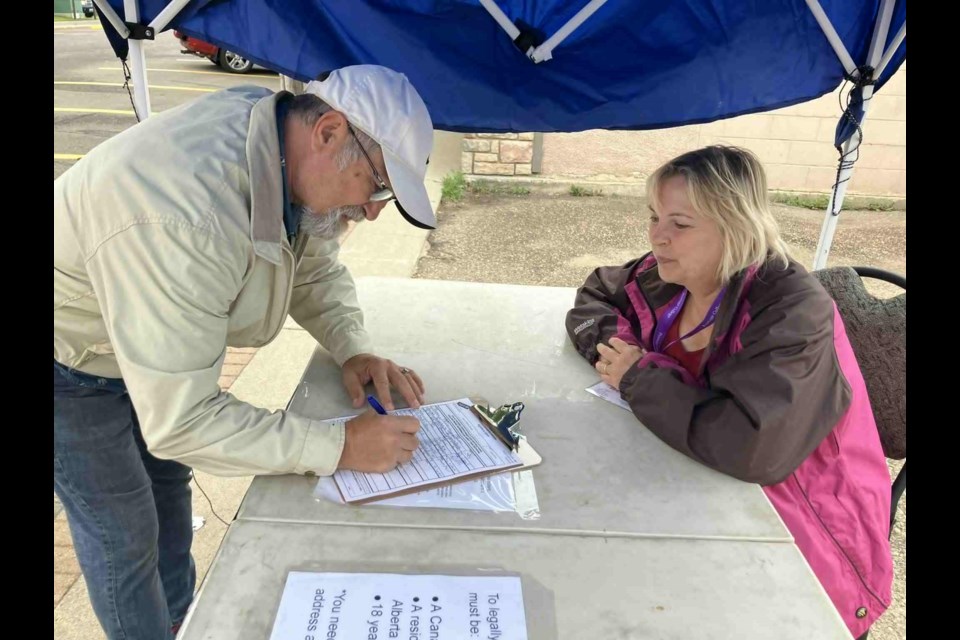 Marvin Straus talks with Chris McCullough as he signs the Alberta Forever Canada petition on Aug. 13. McCullough, a resident of Lac La Biche, is helping out with the provincewide campaign, which was started by former provincial MLA Thomas Lukaszuk to keep Alberta in Canada instead of separating. Chris McGarry photo. 