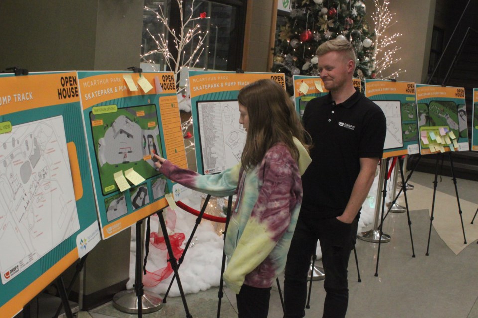 Kyle Sheppard of Drop In Skateparks shows Maya White some of the proposed designs on display at the open house which took place inside the Bold Centre lobby on Dec. 6. Chris McGarry photo. 