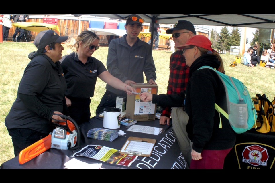  Lori A. Lemay, Angelica Webb, and Lyric Jesso, members of Lac La Biche County Fire Rescue, talk with Mike and Heather Dempsey about the FireSmart program during an event that took place at  Holowachuk Estates Park on May 15. Chris McGarry photo. 