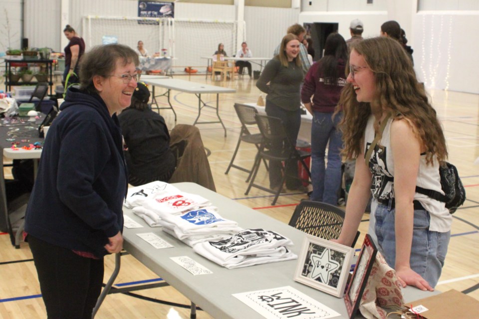 Winter Oberg, a Grade 11 student at JA Williams (JAWS) High School in Lac La Biche, shares a laugh with Melanie D’Souza, who stopped by the young entrepreneur’s table to check out the Lino printed t-shirts she had on offer. Oberg was amongst the large group of students who sold homemade products at the entrepreneur fair, which took place on May 8 at the Bold Centre. Chris McGarry photo. 