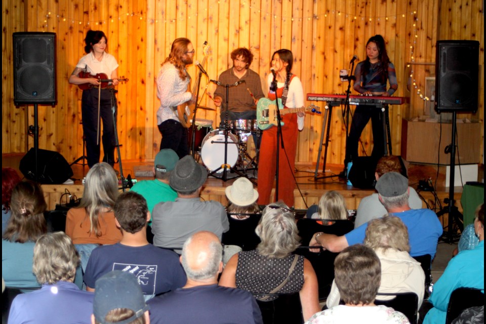 The Calgary-based cinematic neo-folk group Melyssa Lee and the Education Party band performed onstage inside of the Sir Winston Churchill Provincial Park campground amphitheatre for the July 19 edition of the 2025 Music in the Forest concert series. 
In front, from left to right; Jerevieux (bass) and Melyssa (lead vocals and guitar). Back row, left to right; Elspeth Bruce (violin), Dan Abelseth (drums), Cindy Ma (keyboards). Chris McGarry photo. 
