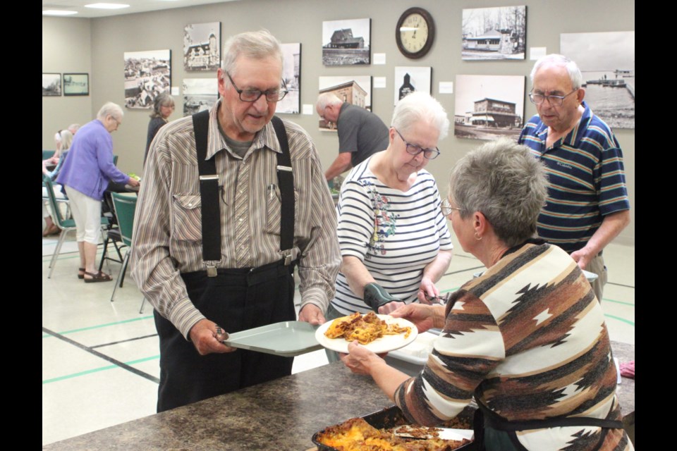 Donna Fabbro scoops lasagna onto a plate for Morris Lamoureux at the ‘Eat to Live’ event. Chris McGarry photo.
