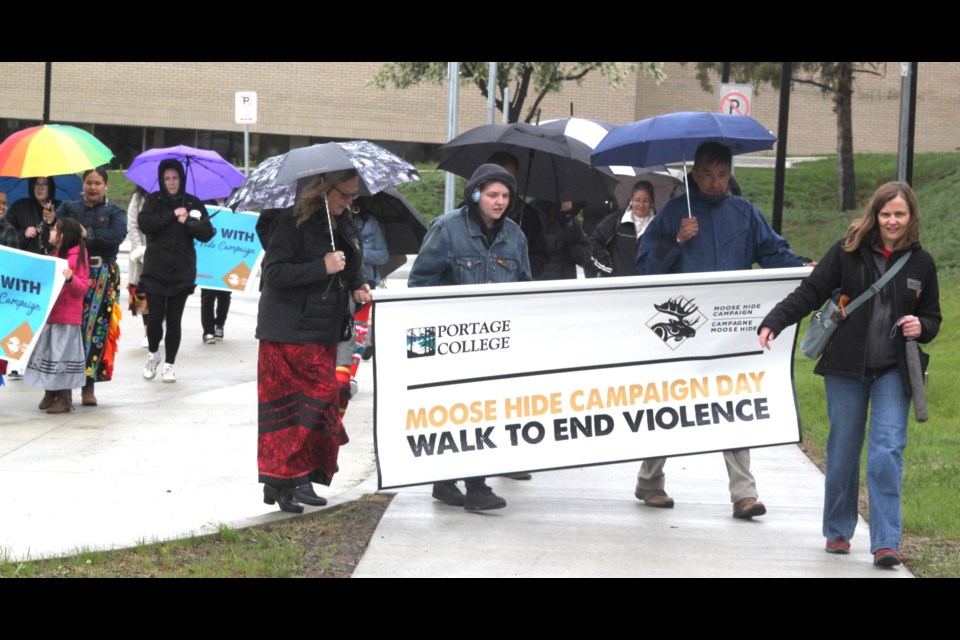 Portage College president Nancy Broadbent, Mel Broadbent, Jason Nest and Jaime Davies carry the Moose Hide Campaign banner during the walk that took place on May 15. Chris McGarry photo. 