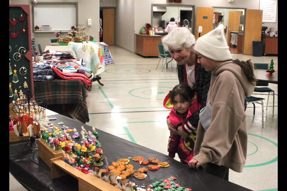 Odile Wowk and her granddaughters-Lilly and Rose Bobocel-check out the figurines that were on sale at the craft sale. Chris McGarry photo. 