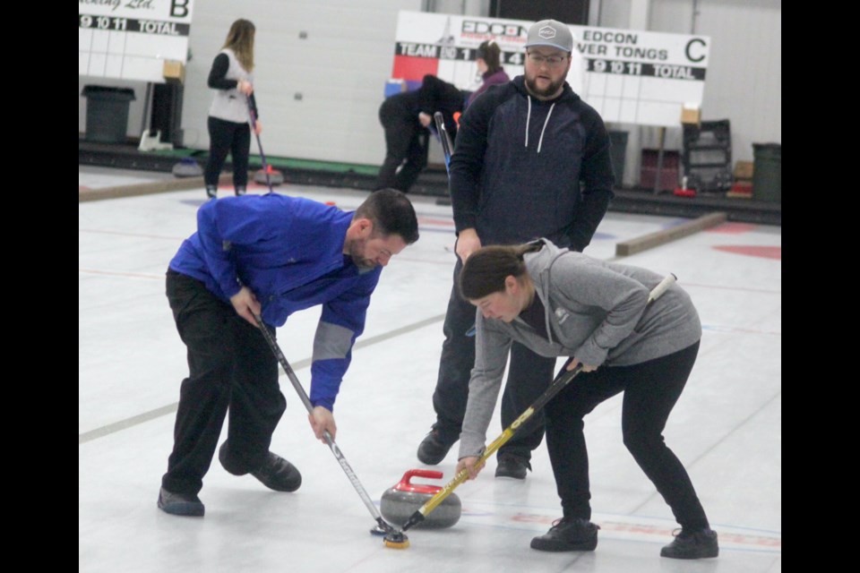 Mike Teeter, who served as skip for a Plamondon team, watches as Steve Reid and Heather Reid start sweeping during the Mixed Bonspiel that took place from April 4-7. Taylor Watson (not in photo) was also on the team who won first place in the C Division. Chris McGarry photo. 