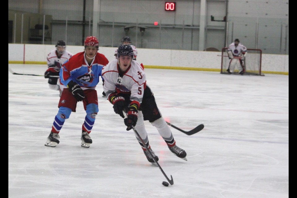 A member of the Northern Alberta Lightning looks on as Lac La Biche Lakers forward Raiden Perkins moves with the puck towards the opposing team’s zone during the during Friday’s match at the Bold Center in which the Lakers defeated the Lightning 6-5 in overtime. Chris McGarry photo. 