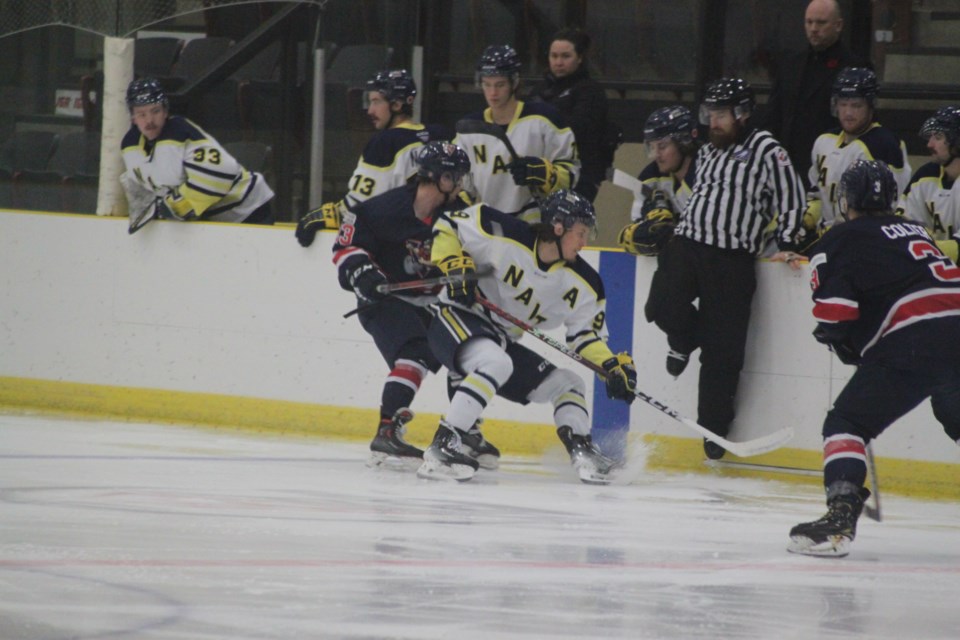 A referee moves out of the way as Voyageurs forward Mason Beck slams into the back of the NAIT OOKs’ Bjorn Robinson. Chris McGarry photo. 