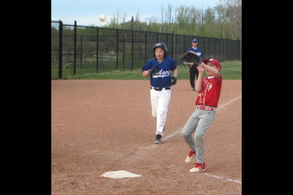 Ryan Kuraitis of the Lac La Biche Dodgers makes a run for home plate as St. Paul Storm player Mason Brodziak waits to catch the ball to tag him before he can arrive safely home home during the May 13 game between the two U11 Lakeland Minor Ball squads. The game, which took place at the Bold Centre ball diamond three, resulted in a narrow 18-17 victory for St. Paul. Chris McGarry photo. 