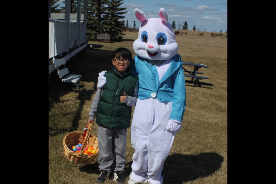 Sebastian Dela Rosa stands with the Easter Bunny after collecting a basketful of colourful Easter eggs that were hidden around the grounds of the Lac La Biche Mission for the 'Easter at the Mission' event, held on April 19. Chris McGarry photo. 