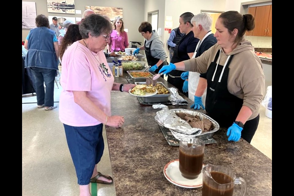 Sharon Hutchinson receives some food from Lisa Grammer during the Seniors Week meal and bake auction that took place at the Lac La Biche Heritage Society on June 4. Chris McGarry photo. 