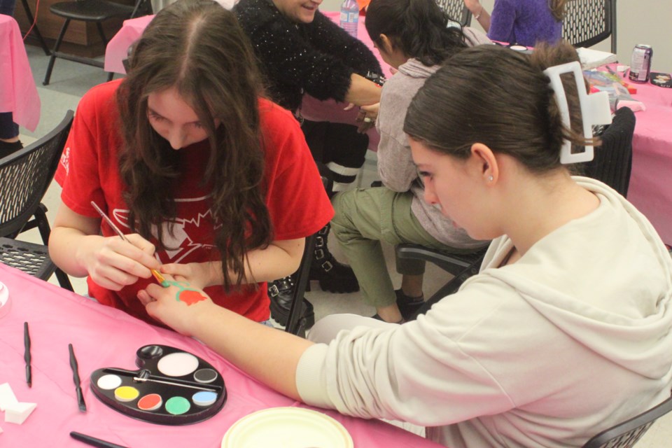 Zoya Ennest paints a rose on Alivia Worbeck's hand. Chris McGarry photo. 