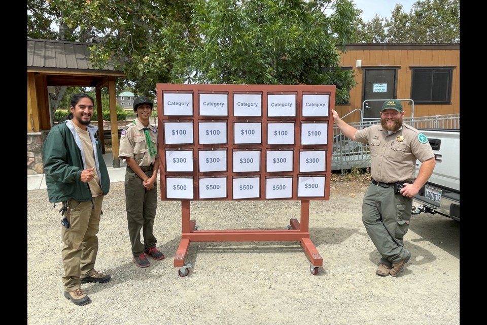 Shawn Bawa (second from left) delivers the finished "Jeopardy!" board to his Livermore mentor Seth Eddings (right).