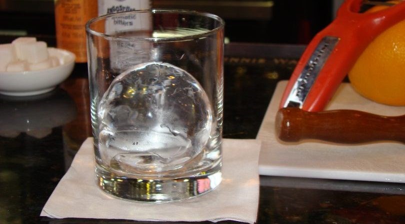 Christ Norton stands before hand carved block of ice and ingredients for specialty Frisco cocktail