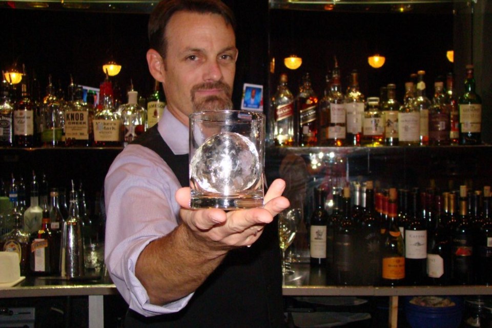 Chris Norton bartending holds up ice sculpted specialty cocktail in Frisco Edoko Sushi