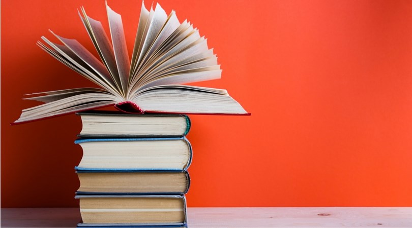 Plano books clubs stack of fanned books on red background