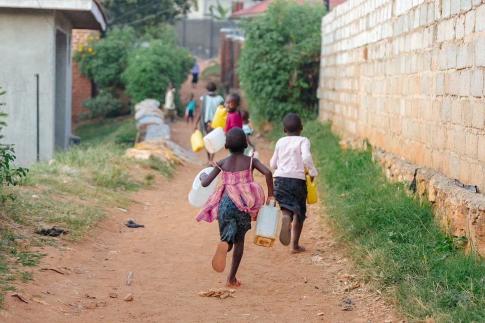 Children,Carrying,Water,Cans,In,Uganda,,Africa