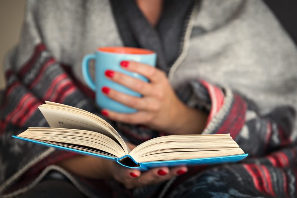 Woman,Reading,A,Book,And,Holding,A,Mug,Of,Hot
