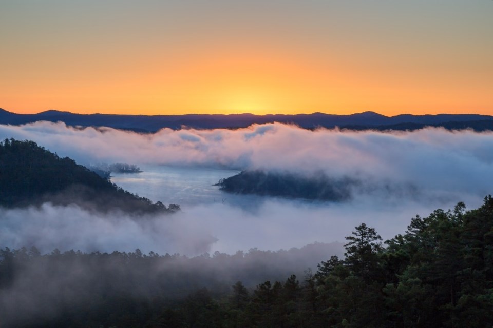 The sun rises on a foggy morning at Broken Bow Lake in Oklahoma.