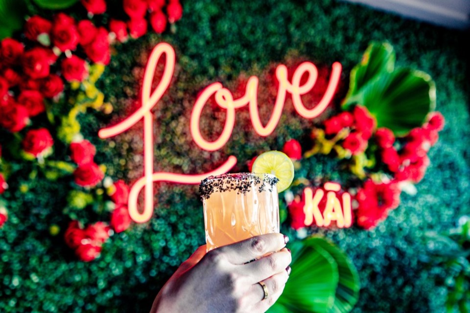 A hand holds up a drink in front of a sign.