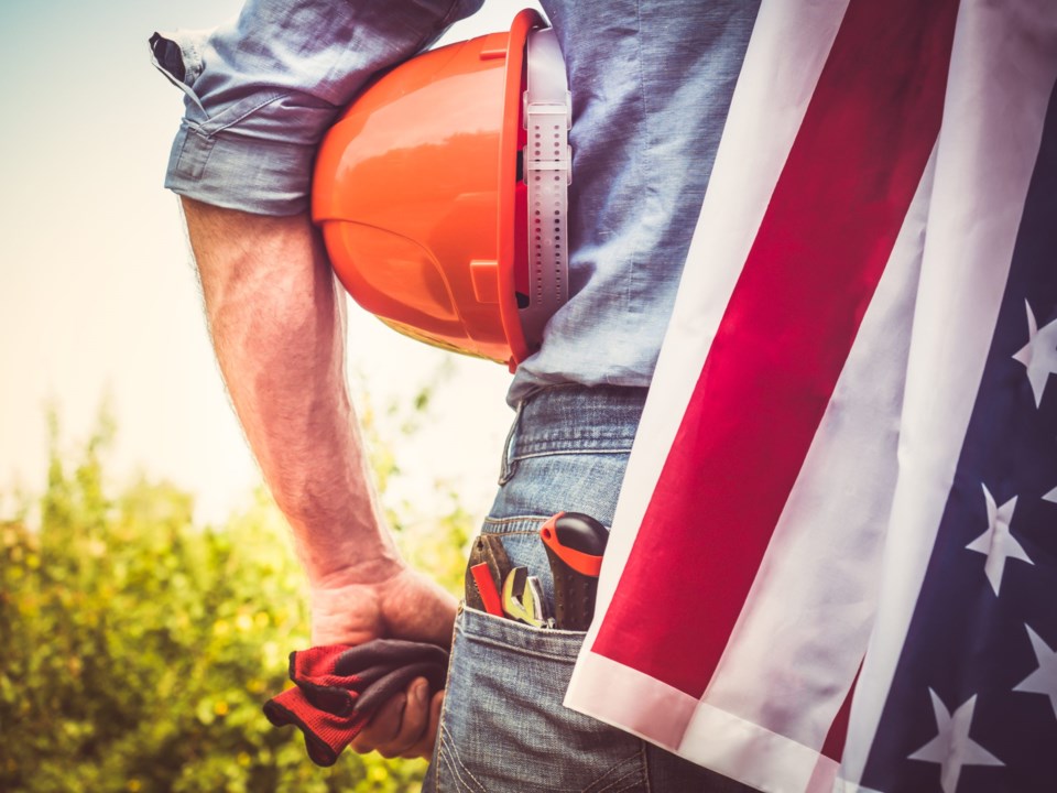 Attractive,Man,In,Work,Clothes,,Holding,Tools,And,A,Us