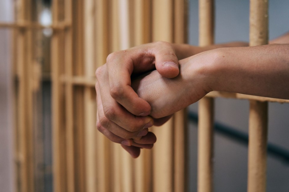 Young,Man,Behind,Bars.,Man&#8217;s,Hands,Resting,On,The,Bars