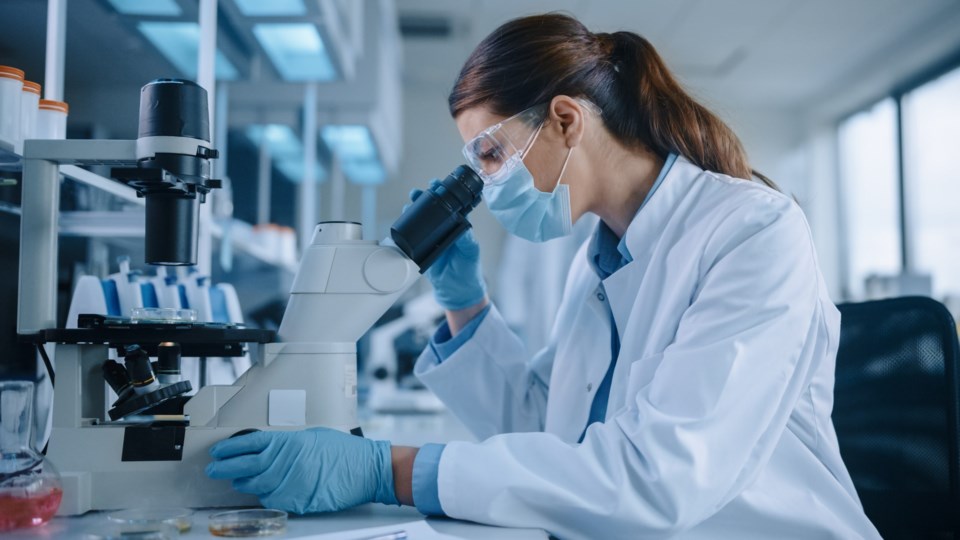 Female,Scientist,In,Face,Mask,And,Glasses,Looking,A,Petri