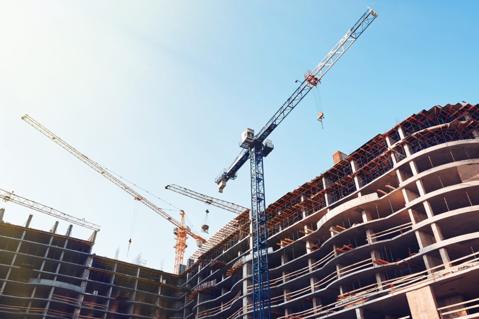 High,Building,Under,Construction.,Side,With,Cranes,Against,Blue,Sky