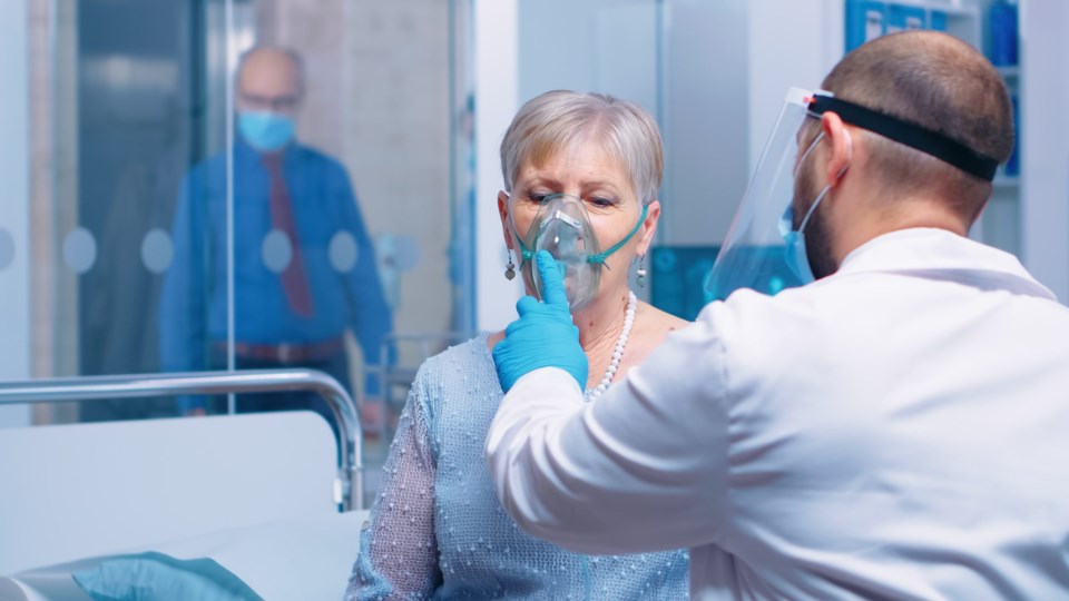 Doctor,In,Mask,And,Visor,Helping,Old,Lady,To,Breathe
