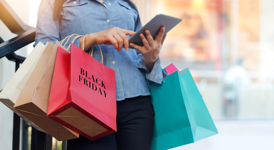 Woman,Using,Tablet,And,Holding,Black,Friday,Shopping,Bag,While