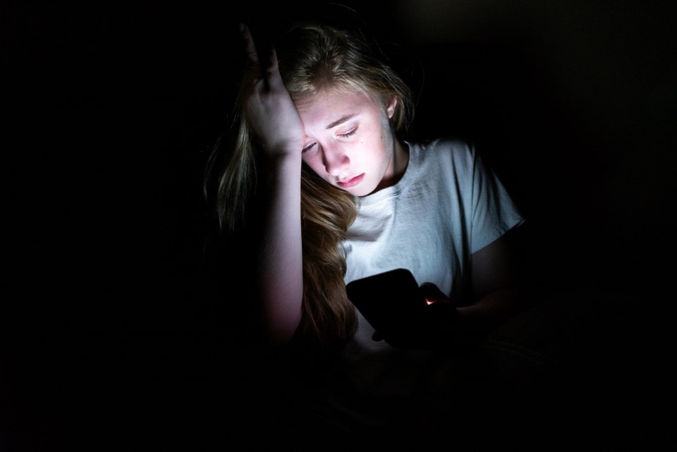 Upset,Girl,Sitting,In,The,Dark,While,Using,Her,Smartphone.