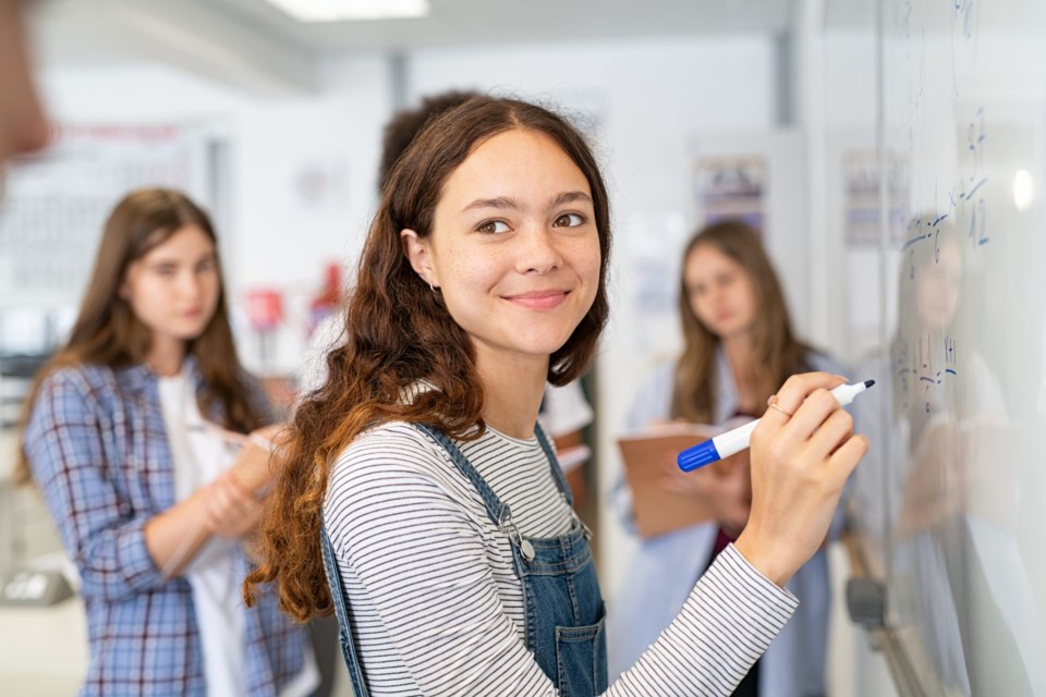 Portrait,Of,Smiling,Girl,Solving,Math,Equation,On,White,Board.